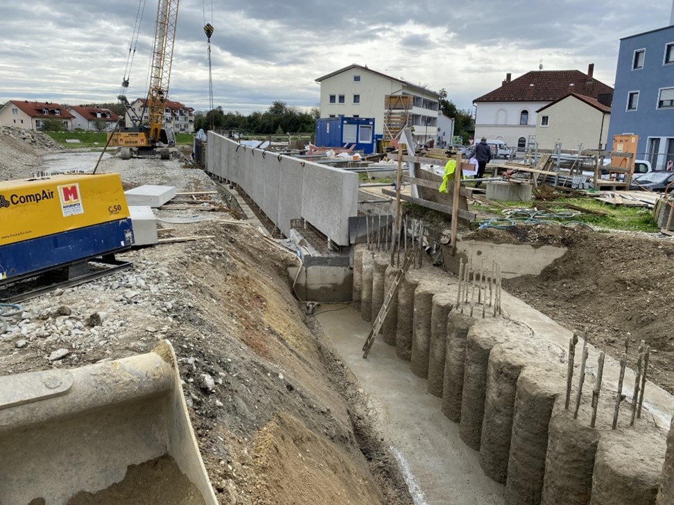 Abschnitt II - BA 04 – Bild 2 Versetzen der neuen Fertigteilwände rechtsufrig (Blick Richtung Südost, von der Bachstraße Richtung Kreuzberger Weg Brücke). Mit einem Mobilkran werden die neuen Fertigteilwände auf den Bohrpfählen platziert.