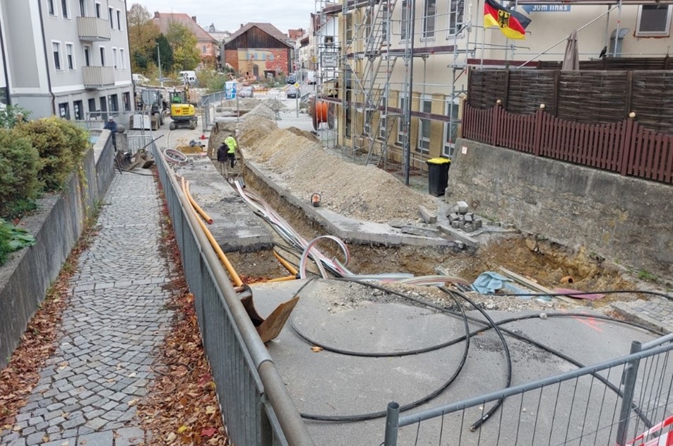 Abschnitt II/III – vorgezogene Spartenverlegungen – beispielhaft hier in der Passauer Straße (Blick West, von Brücke Passauer Straßen - von Erlach kommend - Richtung Stadtmitte). Arbeiter verlegen im offenen Leitungsgraben im Fahrbahnbereich Versorgungsleitungen.