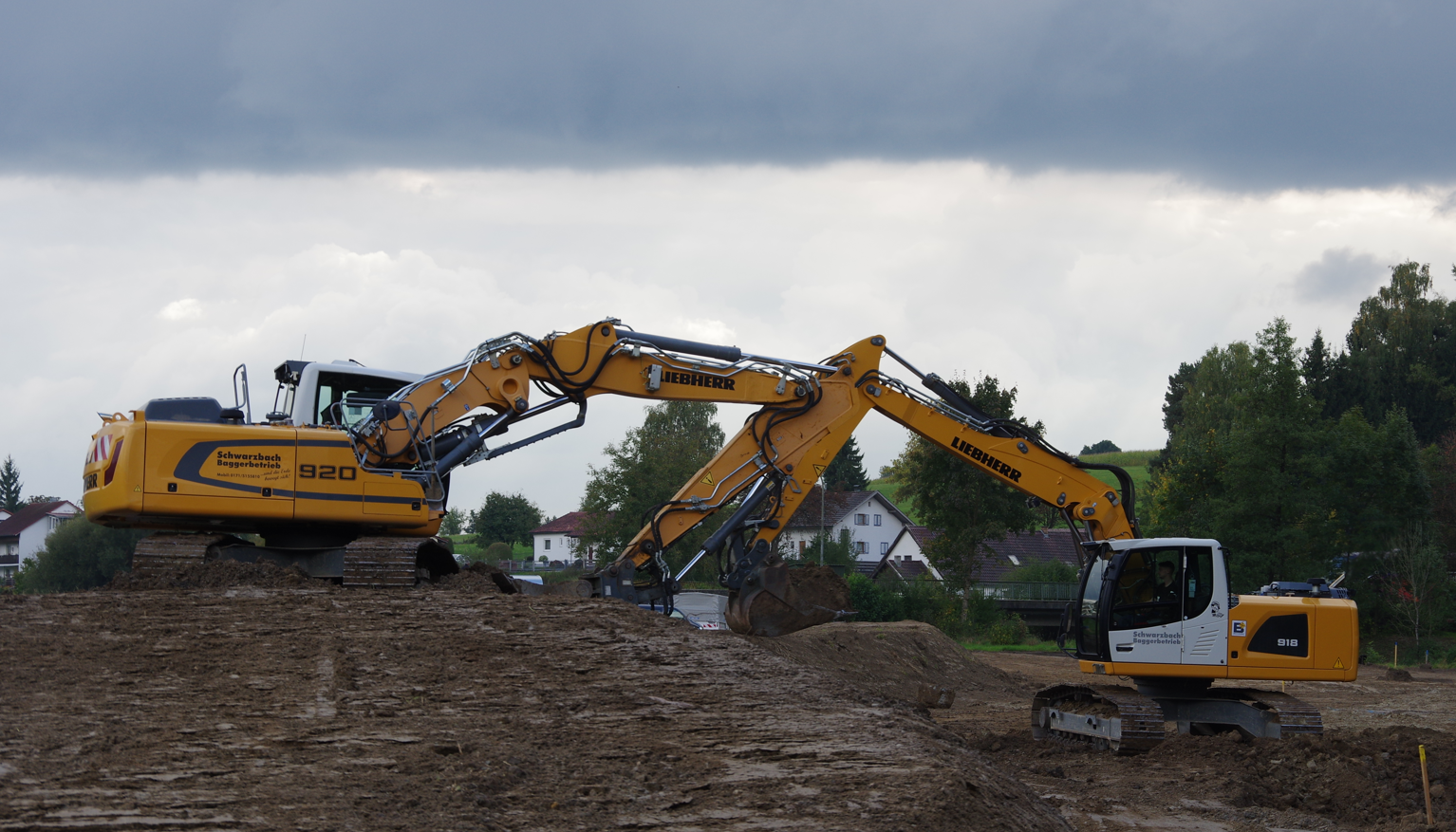 Die beiden Bagger arbeiten Hand in Hand, auch wenn sich der Himmel verdunkelt Zwei Bagger arbeiten auf der Baustelle.